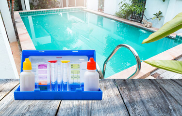 Water tester test kit on wooden table over turbid swimming pool water background, quality water testing test kit, pool maintenance and service business concept