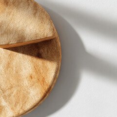 Wooden cheese board with shadow on white background