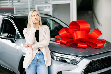 Thoughtful businesswoman choosing new car in dealership showroom