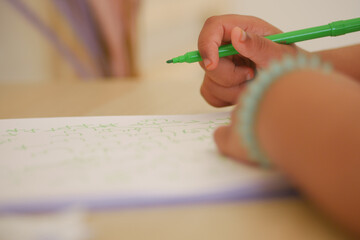 Child practicing writing with a green marker at home