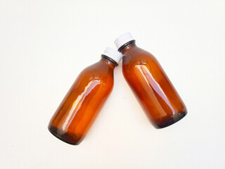 Amber glass bottles with aluminum caps laying on a white background, two brown glass bottle for pharmaceuticals, syrups, essential oils, and cosmetics,