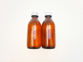 Amber glass bottles with aluminum caps laying on a white background, two brown glass bottle for pharmaceuticals, syrups, essential oils, and cosmetics,