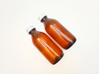 Amber glass bottles with aluminum caps on a white background, two brown glass bottle for pharmaceuticals, syrups, essential oils, and cosmetics,