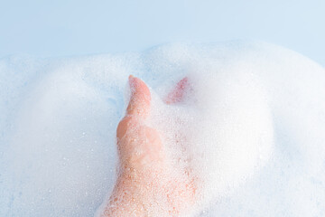 Woman's hand in delicate white foam cosmetics, bath foam, shower gel, soap. The concept of SPA, water treatments. A copy of the space.