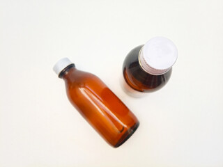 Amber glass bottles with aluminum caps on a white background, two brown glass bottle for pharmaceuticals, syrups, essential oils, and cosmetics,