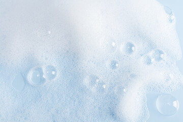 Abstract background of white soap foam texture. shampoo, shower gel with bubbles. delicate blue white cosmetic background.