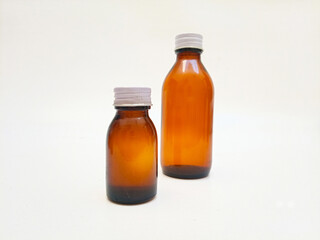 Two Amber glass bottles with aluminum caps on a white background, brown glass bottle for pharmaceuticals, syrups, essential oils, and cosmetics
