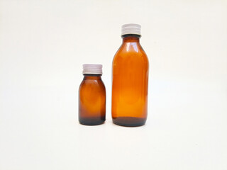 Two Amber glass bottles with aluminum caps on a white background, brown glass bottle for pharmaceuticals, syrups, essential oils, and cosmetics