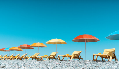 Colorful Beach Umbrellas and Sun Loungers on a Pebble Seaside