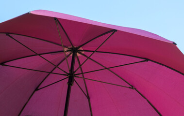 A pink umbrella with a blue sky in the background