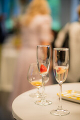 Glasses adorned with strawberries sit on a table amidst a lively atmosphere of celebration