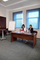 Two business women work in the office to solve problems and sign agreements.