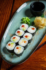 Sushi rolls beautifully arranged on a plate, with spicy sauce and delicate garnishes