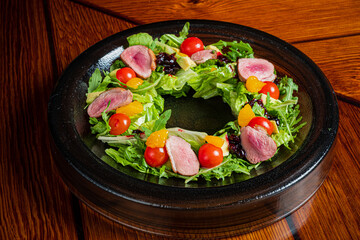 A vibrant circular salad showcases fresh greens, cherry tomatoes, and citrus segments