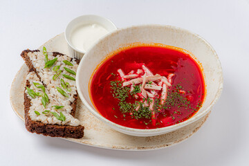 Bright beet soup garnished with herbs, served with dark rye bread and creamy topping