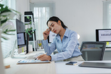 Asian businesswoman having a headache while working with financial graph at the office
