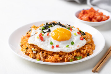 Kimchi fried rice with fried egg, pork, sesame seed, chili, spring onion and seaweed on white plate, Korean food