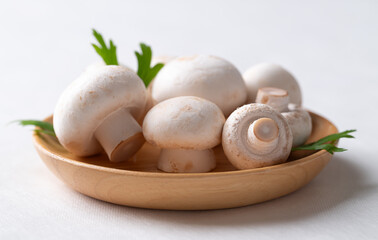 White Button mushroom or Champignon mushroom (Agaricus bisporus) on wooden plate, Food ingredient