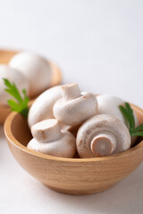 White Button mushroom or Champignon mushroom (Agaricus bisporus) in wooden bowl on white background, Food ingredient