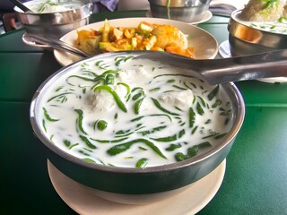 a bowl of cendol with coconut milk and ice, served alongside a portion of rojak