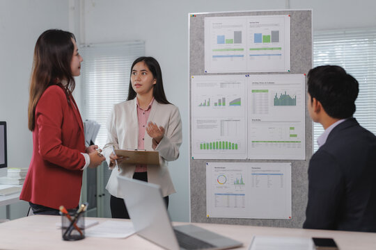 Team of business professionals discussing data analysis with charts and graphs on a board, focusing on collaborative decision making