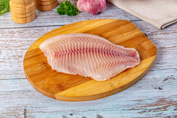 Raw tilapia fish fillet over board