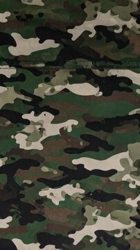 Detailed video of a classic dark woodland camouflage pattern with greens, brown and blacks with textured fabric material detail, full frame.