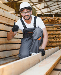 Carpenter showing thumbs up while working with wood planks in warehouse