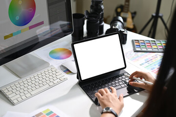 Photographer working on digital tablet with color charts and editing tools on desk