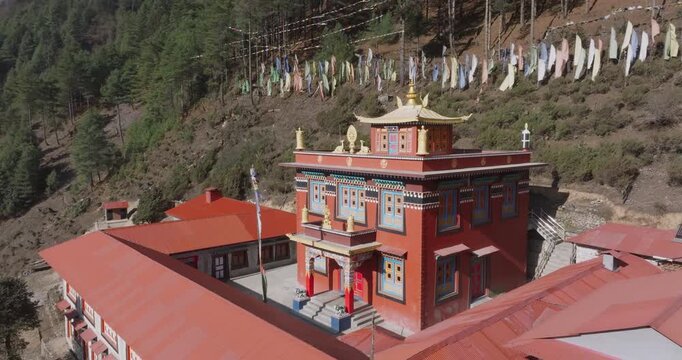 Aerial view of serene Buddhist temple Monastry in Nepal, surrounded by lush forest and adorned with vibrant prayer flags in peaceful highland landscape