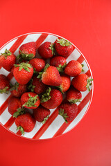Monochromatic strawberries on striped red plate.