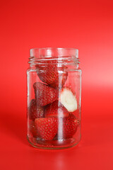 Juicy Red Strawberries In Glass Jar On Red Backdrop