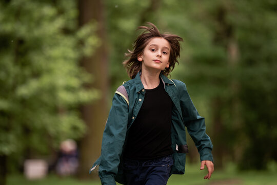 A child boy is running with wind blowing in his hair.