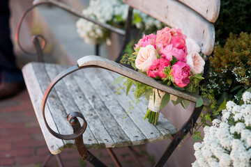 Bridal bouquet placed on rustic bench with garden flowers nearby