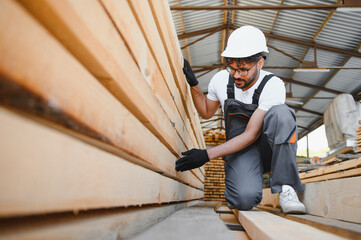Carpenter inspecting wooden planks in lumber warehouse