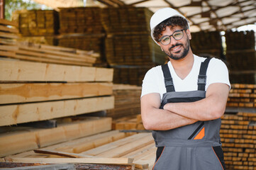 Woodworker smiling with crossed arms in lumber warehouse