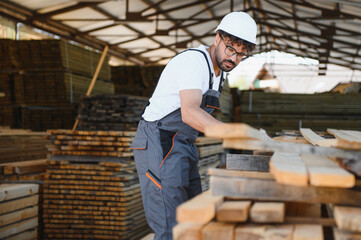 Carpenter inspecting wooden planks in lumber warehouse