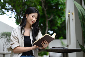 Young woman enjoying a peaceful moment reading a book at an outdoor cafe