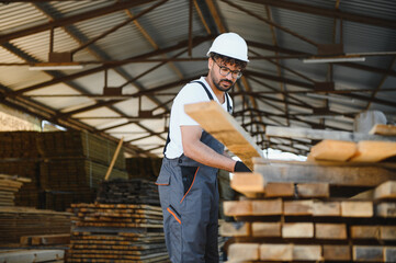 Fototapeta premium Carpenter working with wood planks in timber warehouse