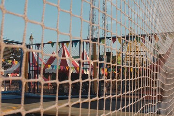 Trampoline and Festival Scene Viewed Through Protective Netting