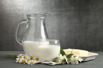 Fresh dairy products and flowers on grey wooden table against textured background
