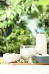Different fresh dairy products and flowers on white table outdoors