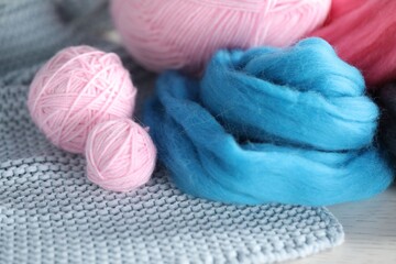 Soft felting wool and knitting yarn on white wooden table, closeup