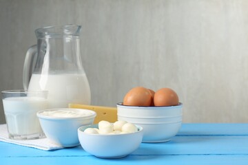 Different dairy products and eggs on light blue wooden table, space for text