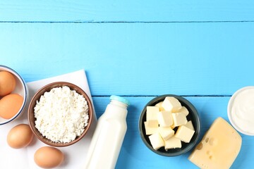 Different dairy products and eggs on light blue wooden table, flat lay. Space for text