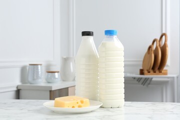 Milk and cheese on white marble table indoors. Dairy products