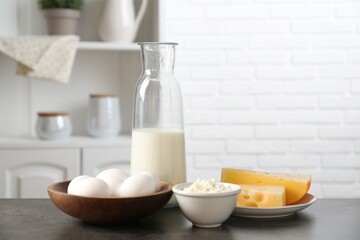 Different dairy products and eggs on gray textured table in kitchen