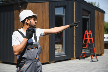 Construction worker directing modular house placement with walkie talkie