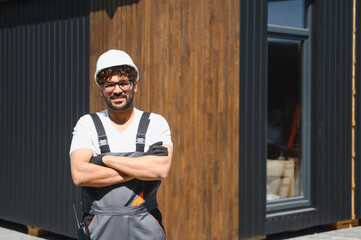 Smiling engineer overseeing modular house construction