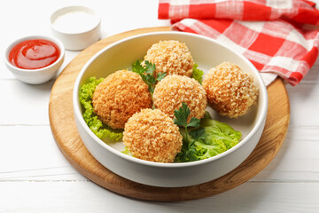 Delicious fried croquette balls with parsley and lettuce on white wooden table, closeup